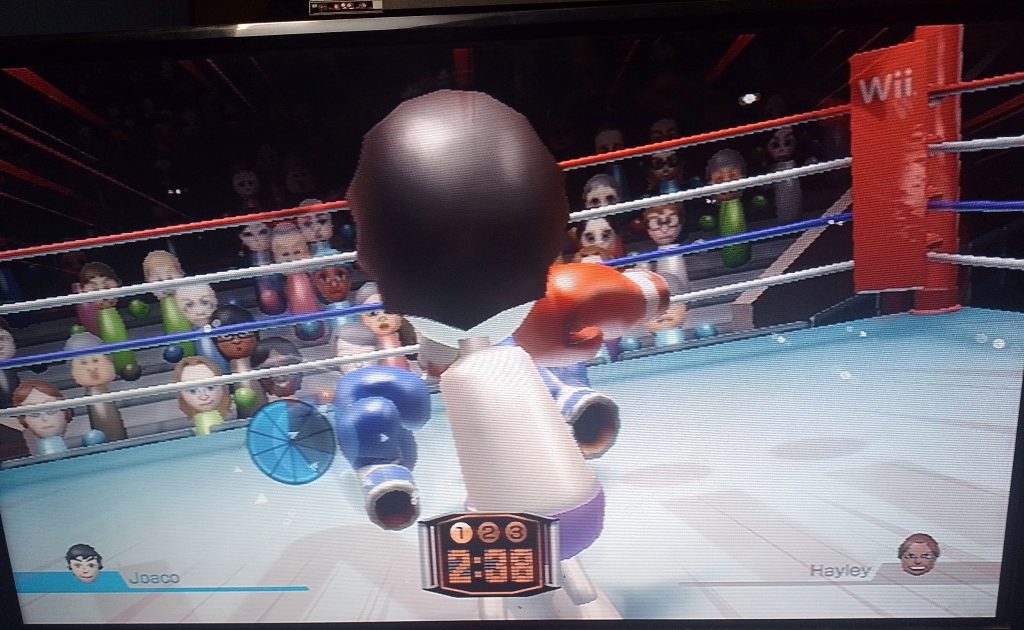 Pantalla mostrando en su interior el videojuego "Wii Sports". En este se ve una lucha de boxeo entre 2 personajes animados al interior de un ring de box. 