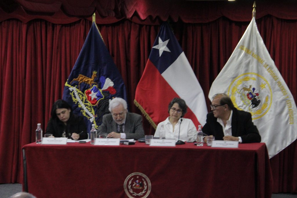 La académica de la Universidad de Chile Mireya Dávila, y el ex ministro de Defensa Francisco Vidal, escuchando a José Elizondo durante la conferencia.